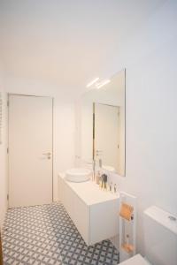 W białej łazience znajduje się umywalka i lustro. w obiekcie Liiiving in Porto - Boho Blue Home w Porto