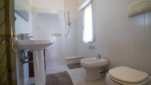 Un baño blanco con inodoro y lavabo. en La Casa di Anita, en Orosei