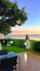 a woman in a white dress taking a picture of the ocean at Harris elegant house superb view near airport in Artemida