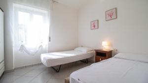 Dos camas en una habitación blanca con ventana. en La Casa di Anita, en Orosei