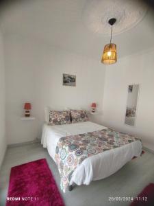 a white bedroom with a bed and a lamp at Apartamentos das Avós-Bélise in Nazaré +7 photos