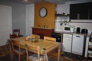 uma cozinha com uma mesa e um relógio na parede em La Gâtinaise em Châtillon-Coligny