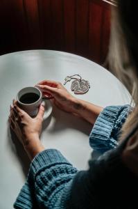una mujer sentada en una mesa con una taza de café en Bellagio Mini Resort - no coração de Gramado, en Gramado