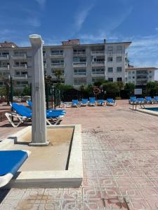 a large building with blue lounge chairs in front of it at APCOSTAS Els Pins Lotus in Blanes