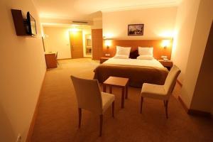 VelimeşeにあるShilla Hotelのベッド、テーブル、椅子が備わるホテルルームです。