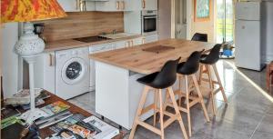 cocina con mesa de madera y taburetes en Maison de 4 chambres avec piscine privee et wifi a Saint Germain du Pert a 5 km de la plage, en Saint-Germain-du-Pert