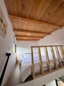 Posto letto in camera con soffitto in legno. di Corinto Tiny House a Paipa