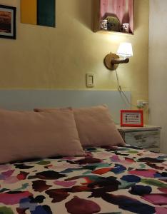 una cama con un edredón colorido y una lámpara en Studios La Bella Vida en Escobar en Belén de Escobar