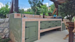 an outdoor kitchen with green doors and a stone wall at Bonvivan House in Diminići