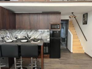 a kitchen with wooden cabinets and a black refrigerator at Elegant Loft 2 in Alexandroupoli