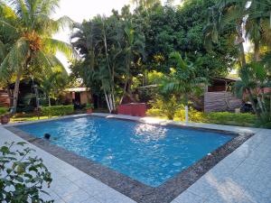 a swimming pool in a yard with palm trees at Bungalow chez Mouch Nosy-Be 4 in Nosy Be