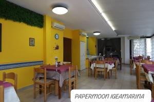 a restaurant with tables and chairs and a yellow wall at PAPER MOON in Bellaria-Igea Marina