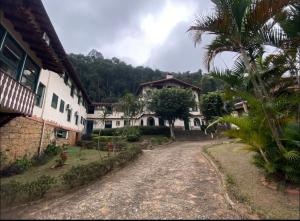 a dirt road in front of a house with a palm tree at Locação temporada na Serra in Petrópolis
