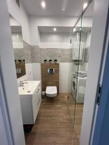 a bathroom with a toilet and a sink and a shower at Apartament Sunrise in Częstochowa +9 photos