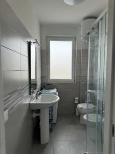 Un baño con lavabo, inodoro y ventana. en Residence Riva del Mulino, en Marina di Montenero