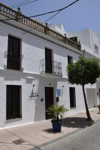 un bâtiment blanc avec un arbre devant lui dans l'établissement Chacón Apartments & Suites, à Estepona