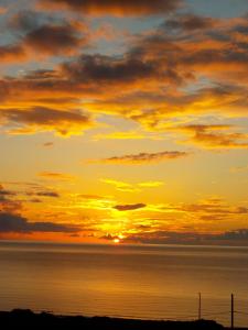 einen Sonnenuntergang über dem Meer mit der Sonne am Himmel in der Unterkunft Golden Sun Apartments in Phalasarna