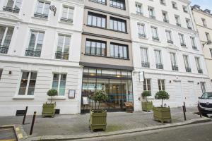 - un grand bâtiment blanc avec des chaises vertes devant dans l'établissement Le Grand Quartier, à Paris