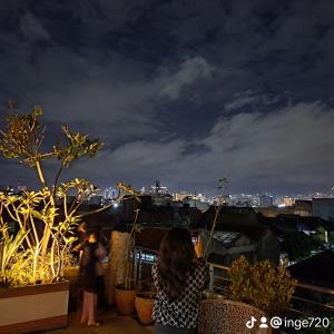 a group of people standing on a rooftop at night at G10 Guest House Near Asia Afrika Bandung in Bandung