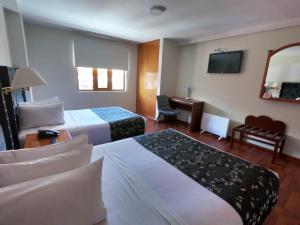プーノにあるCasona Plaza Hotel Punoのベッド2台とデスクが備わるホテルルームです。