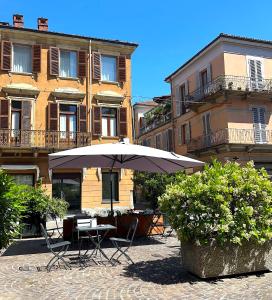 a table with an umbrella in front of a building at Appartamento del Palio in Asti