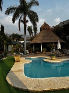 a resort swimming pool with a thatch roof at VILLAS EL ENCANTO in Jalpan