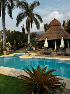 a resort with a swimming pool and a thatched building at VILLAS EL ENCANTO in Jalpan de Serra