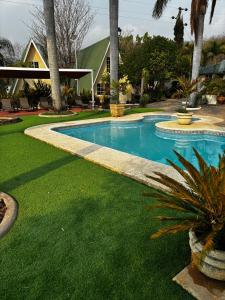 a swimming pool with green grass and a house at VILLAS EL ENCANTO in Jalpan de Serra