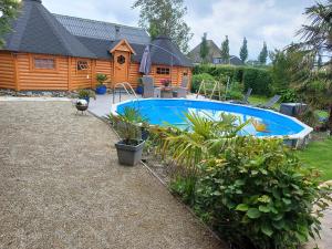a swimming pool in front of a log cabin at Finse Kota met privé Sauna en Hottub in Spanbroek