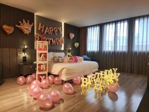 花蓮品悅文旅Hualien Pink Corner Hotel في مدينة هوالين: غرفة نوم بسرير مع بالونات و مجموعة شموع