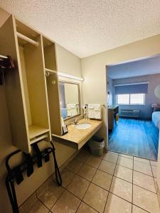a bathroom with a sink and a mirror at Days Inn & Suites by Wyndham Kansas City - Royals Stadium in Kansas City