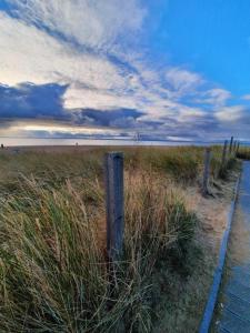 a wooden fence in a field next to the ocean at Apartament Blue Hel in Hel