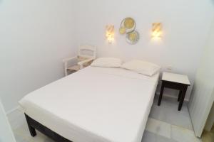 a bedroom with a white bed and a table at Paradise Pirgaki Naxos in Agiassos