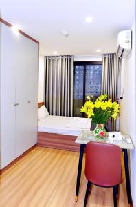 a room with a bed and a table with yellow flowers at Era Apartment Trung Liet in Hanoi