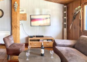 ein Wohnzimmer mit einem Sofa und einem Tisch mit Weingläsern in der Unterkunft Maison de 3 chambres avec jardin clos et wifi a Vendays Montalivet a 7 km de la plage in Vendays-Montalivet