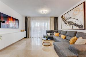 Luxury Holiday House Tenerife في بويرتو دي سانتياغو: غرفة معيشة مع أريكة رمادية وتلفزيون