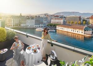 Dos mujeres de pie en un balcón con una mesa en Mandarin Oriental, Geneva, en Ginebra