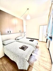 2 Betten in einem Zimmer mit weißen Wänden und Holzböden in der Unterkunft Miramare Apartment Genova in Genua