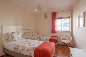 een slaapkamer met 2 bedden, een raam en een stoel bij Apartamento T3 em Pombal in Pombal