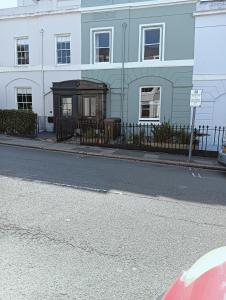 a white building with a black fence and a street at COOKS CABIN in Plymouth