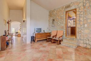 Habitación con pared de piedra, escritorio y sillas. en Finca Can Garbeta by Rentallorca en Manacor