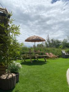 a wooden picnic table with an umbrella on the grass at The Nest Quaint Luxury Cottage Getaway in Tiragarvan