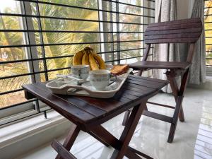 a wooden table with a plate of food and a bowl of bananas at Gintara Homestay by evaddo stays in Kalyānpur +27 photos