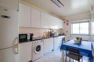 a kitchen with a washing machine and a table at Apartamento T3 em Pombal in Pombal