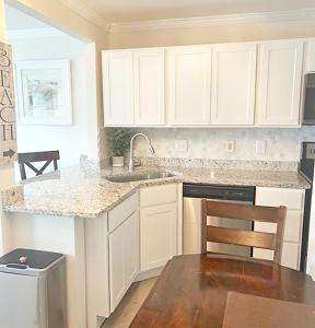 uma cozinha com armários brancos, um lavatório e uma mesa em Sandpiper Cove Unit 8139 Updated Studio In Destin FL em Destin