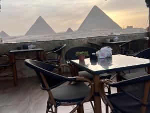 einen Tisch und Stühle auf dem Dach eines Restaurants mit Pyramiden in der Unterkunft Aton pyramids INN in Kairo