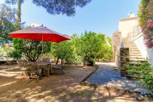 a table and chairs with a red umbrella at SELECT'soHOME - Villa pour 8 personnes avec jacuzzi, vue mer et parking au coeur du Lavandou ! - VILLA MOUN PANTAI in Le Lavandou