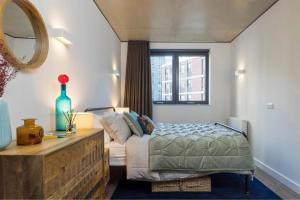 a bedroom with a bed and a couch and a mirror at Botanical-inspired apartments at Repton Gardens right in the heart of Wembley Park in London