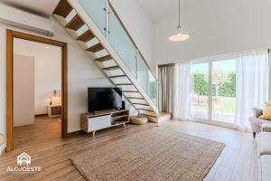 a living room with a tv and a staircase at Páteo Sagaipo in Lourinhã