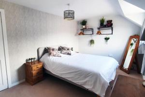 a bedroom with a bed with white sheets and a mirror at York Street Retreat, modern cosy 2 bed with garden in Dufftown